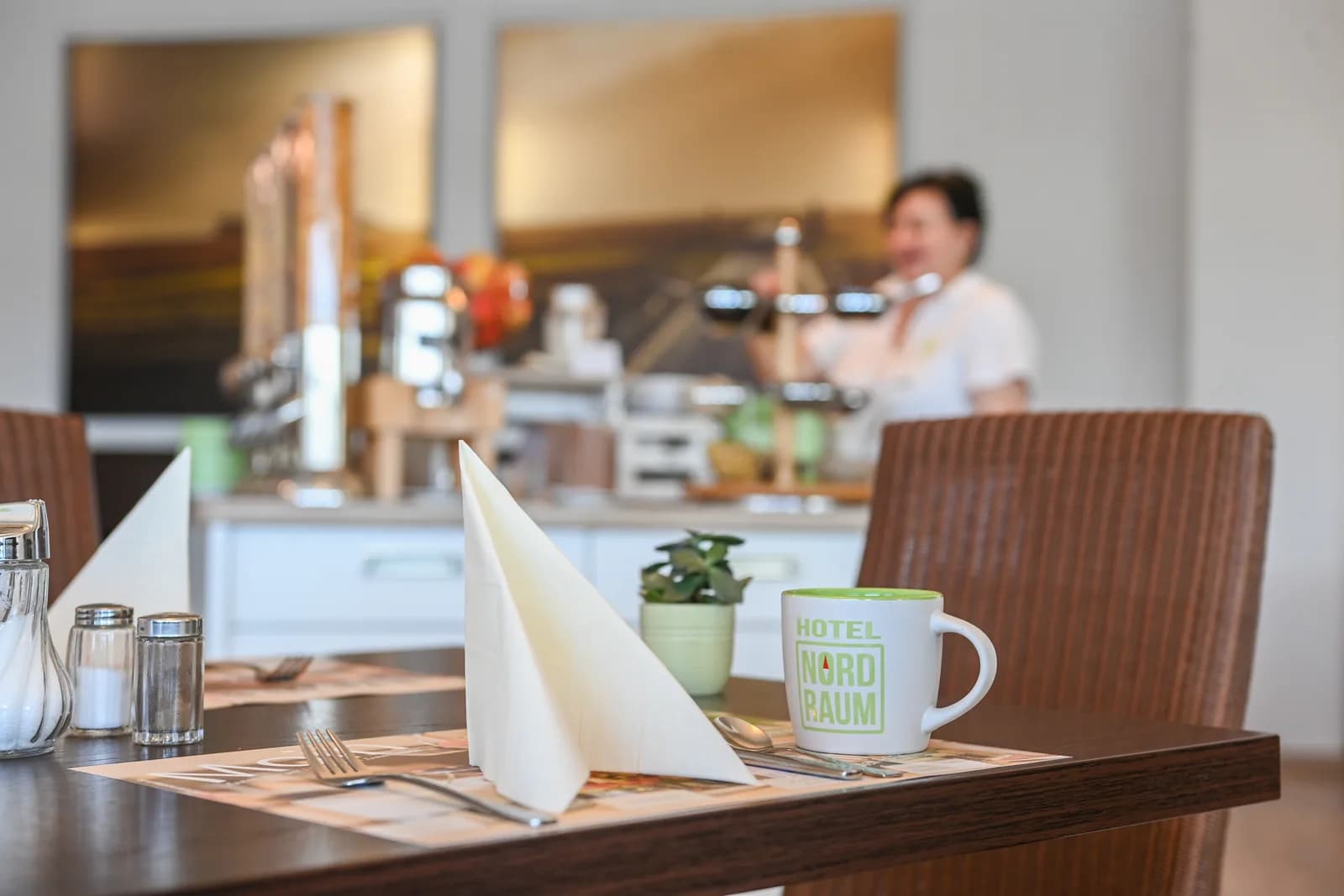 Gedeckter Frühstückstisch mit NordRaum-Tasse, im Hintergrund das Buffet