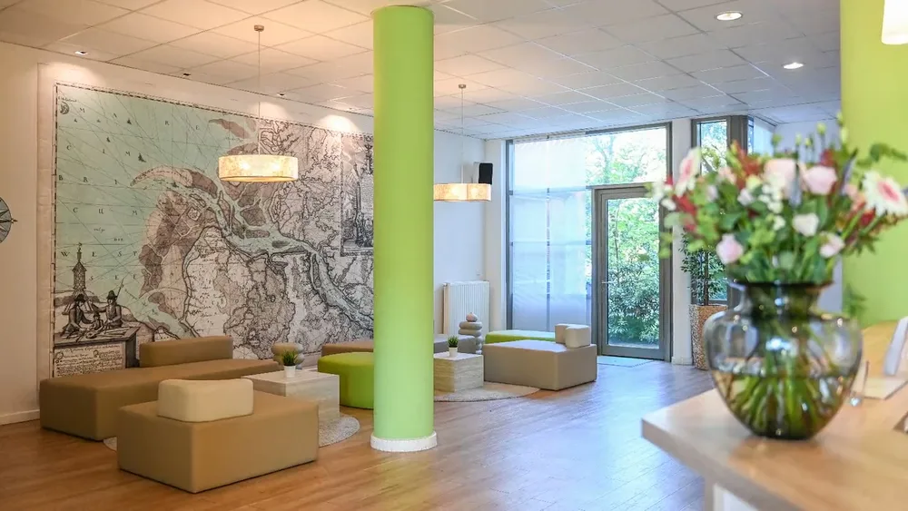 Lobby des Hotel NordRaum mit grüner Säule, Sitzgruppe und Blumenstrauß